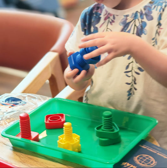 Child playing with colorful building blocks on a green tray