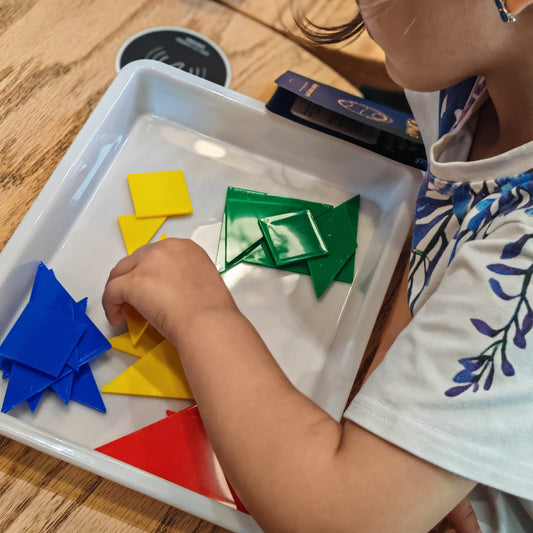 Child playing with colorful geometric shapes on a tray