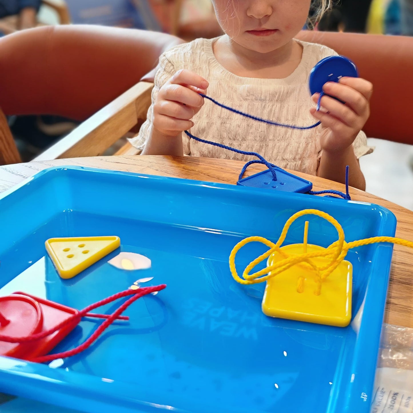 Young girl playing with toys at a table in a casual setting